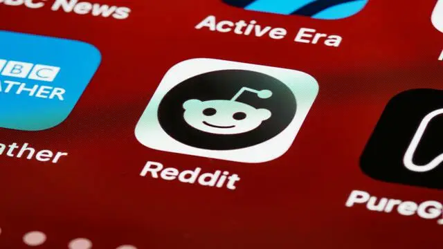 Reddit app icon highlighted on a smartphone screen, alongside other apps.