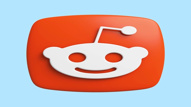 A 3D representation of the Reddit logo with a white smiling alien face on an orange background, set against a light blue backdrop.